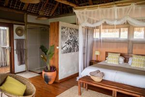 a bedroom with a canopy bed with a table and a couch at Travessia Beach Lodge in Inhambane
