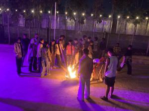 a group of people standing around a fire at night at Road Trip Retreat in Belagula