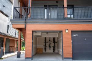 a building with a garage with a balcony on top at The First Tracks Flat in Revelstoke