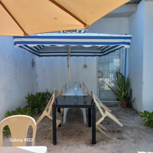 a table and chairs under a blue umbrella at Dhigurah Holidays in Dhigurah