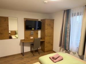 a bedroom with a bed and a desk with a television at Dionysos Traube in Rottweil