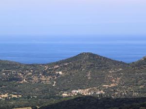 a view of a mountain with the ocean in the background at Hôtel Le Niobel in Belgodère