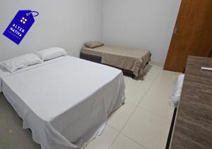 a room with two beds and a blue sign on the wall at Casa Coqueiro 02 in Primavera do Leste