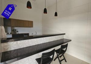 a kitchen with two black chairs at a counter at Casa Coqueiro 02 in Primavera do Leste