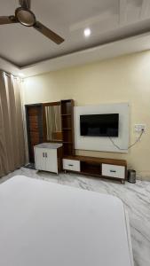 a living room with a flat screen tv and a bed at Hotel Amrindra in Kharar