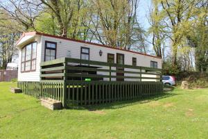 a small white house with a fence in the grass at The Willows at Kingsmead Camping in West Buckland