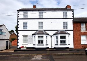 a white house with white doors and windows at Delven House - Self Check-in, Self-Catering Serviced Apartments in Castle Donington