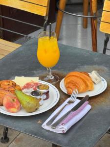 a table with two plates of food and a glass of orange juice at The Culpeper Bedrooms in London