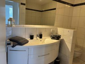 a white bathroom with a sink and a mirror at MeerZeit in Bad Zwischenahn
