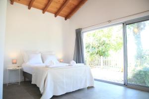 a white bedroom with a bed and a large window at Villa Casa Rosa in Olhão +36 photos