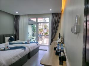 a hotel room with two beds and a window at Tulip Elegant Riverside Hotel in Vang Vieng