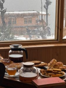 a table with bread and coffee and a window with snow at Weather cottage in Srinagar +15 photos