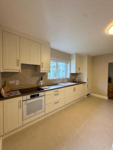 an empty kitchen with white cabinets and a window at Glebe cottage in Kinvara