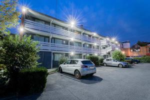 a white car parked in a parking lot in front of a building at Hotel RBX - Roubaix Centre in Roubaix