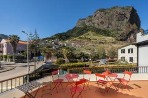 a balcony with a table and chairs and a mountain at Jaca Hostel Porto da Cruz in Porto da Cruz