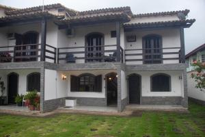 a large white house with a green yard at Casa com 2 suítes com ar in Cabo Frio