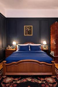 a bedroom with a bed with blue sheets and two lamps at Conacul Fluturilor in Sinaia