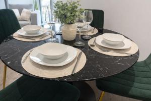 a black table with plates and bowls and glasses on it at Stunning Albert Dock Penthouse in Liverpool +2 photos