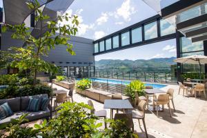 an outdoor patio with tables and chairs and a pool at Hotel Estelar Square in Medellín