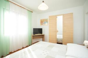 a bedroom with a bed and a television at Apartmani Zlata in Rabac