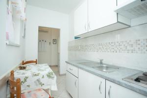 a white kitchen with a sink and a table at Apartmani Zlata in Rabac