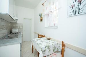 a small kitchen with a table and a sink at Apartmani Zlata in Rabac