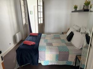 a bedroom with a bed with a quilt on it at Appartement lumineux centre Pau proche château et gare in Pau