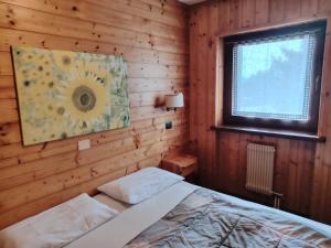 a bedroom with a bed in a wooden wall at APPARTAMENTI LATEMAR con PISCINA e SAUNA in Cavalese +17 photos