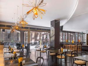 a restaurant with tables and chairs and a chandelier at Mantra on Little Bourke Melbourne in Melbourne