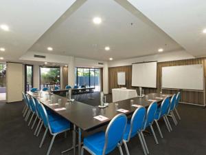 a conference room with a long table and blue chairs at BreakFree Grand Pacific in Caloundra +105 photos