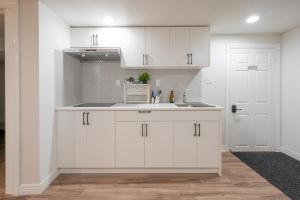 a kitchen with white cabinets and a sink at Comfy Private Basement- Scarborough in Toronto +9 photos