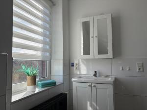 a white bathroom with a sink and a window at Pension Blaue Nordseewelle in Neuharlingersiel +41 photos