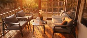 a porch with two chairs and a couch and a table at Chalet Bosrust met serre & privéparking Natuur nabij Maastricht in Lanaken