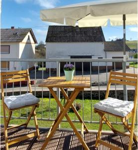 a table and two chairs and an umbrella on a balcony at Ferienwohnung Eifelherzen in Demerath