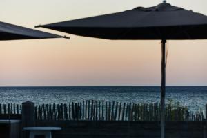 an umbrella on the beach next to a fence at Hôtel Plage Palace & Spa in Palavas-les-Flots +143 photos