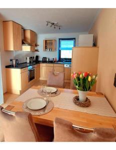 a kitchen with a table with plates and flowers on it at Ferienwohnung Eifelherzen in Demerath