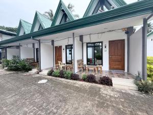 a white house with a porch with wooden doors at Seaside traveler's Inn by Camiguin Island Home in Catarman