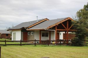 a house with a wooden fence in front of it at Casa Grande con Tinaja a 10 minutos de Lago Puyehue y Rupanco Ruta 215 Internacional in Puyehue