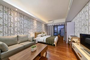 a hotel room with a bed and a couch and a tv at Guangzhou Bokeshijia Hotel in Guangzhou