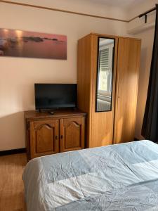 a bedroom with a bed and a flat screen tv at Studio chez Zhang in Differdange