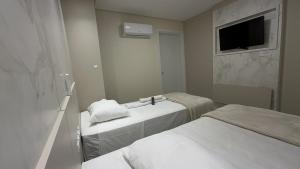 ein weißes Zimmer mit zwei Betten und einem Spiegel in der Unterkunft Hotel Maichel in Erval Velho + 6 Fotos