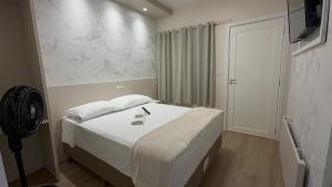 ein Schlafzimmer mit einem weißen Bett und einem Fernseher in der Unterkunft Hotel Maichel in Erval Velho