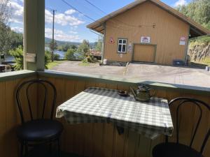a table and chairs on a porch with a building at Hen Stasjon Banevokterboligen in Hen