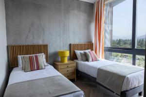 two beds in a room with a window at Pueblo La Dehesa in Santiago