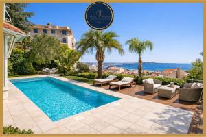 a villa with a swimming pool and palm trees at Villa Blue Riviera & Le Joyau de la baie de Cannes in Cannes
