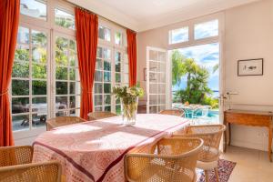 a dining room with a table and chairs and large windows at Villa Blue Riviera & Le Joyau de la baie de Cannes in Cannes
