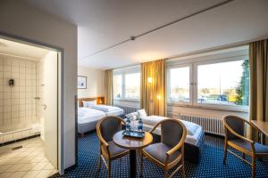 a hotel room with two beds and a table and chairs at Raststättenhotel Tecklenburger Land West in Tecklenburg
