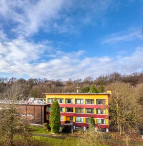 a yellow building with trees in front of it at Raststättenhotel Tecklenburger Land West in Tecklenburg