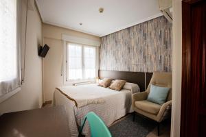a bedroom with a bed and a chair and a window at Pensión Zumardi in Deba