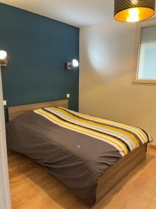 a bed in a room with a blue wall at Agréable maison avec SPA in Crécy-en-Ponthieu